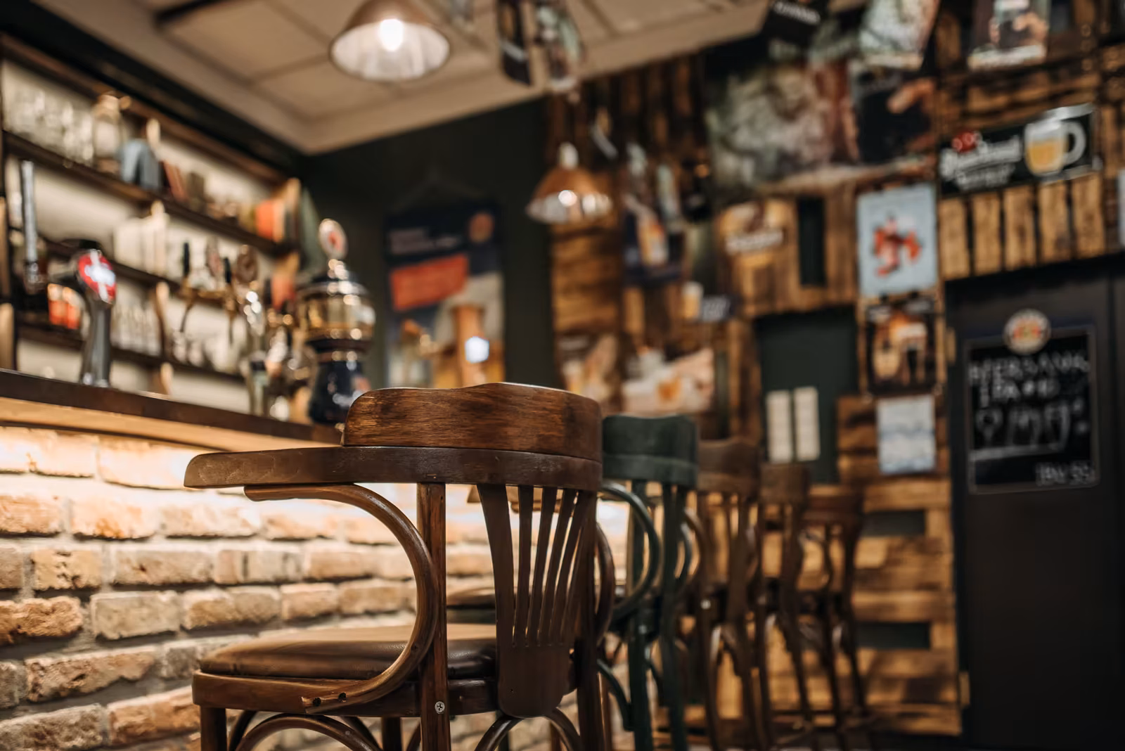 Interior de pub con barra de madera y taburetes.